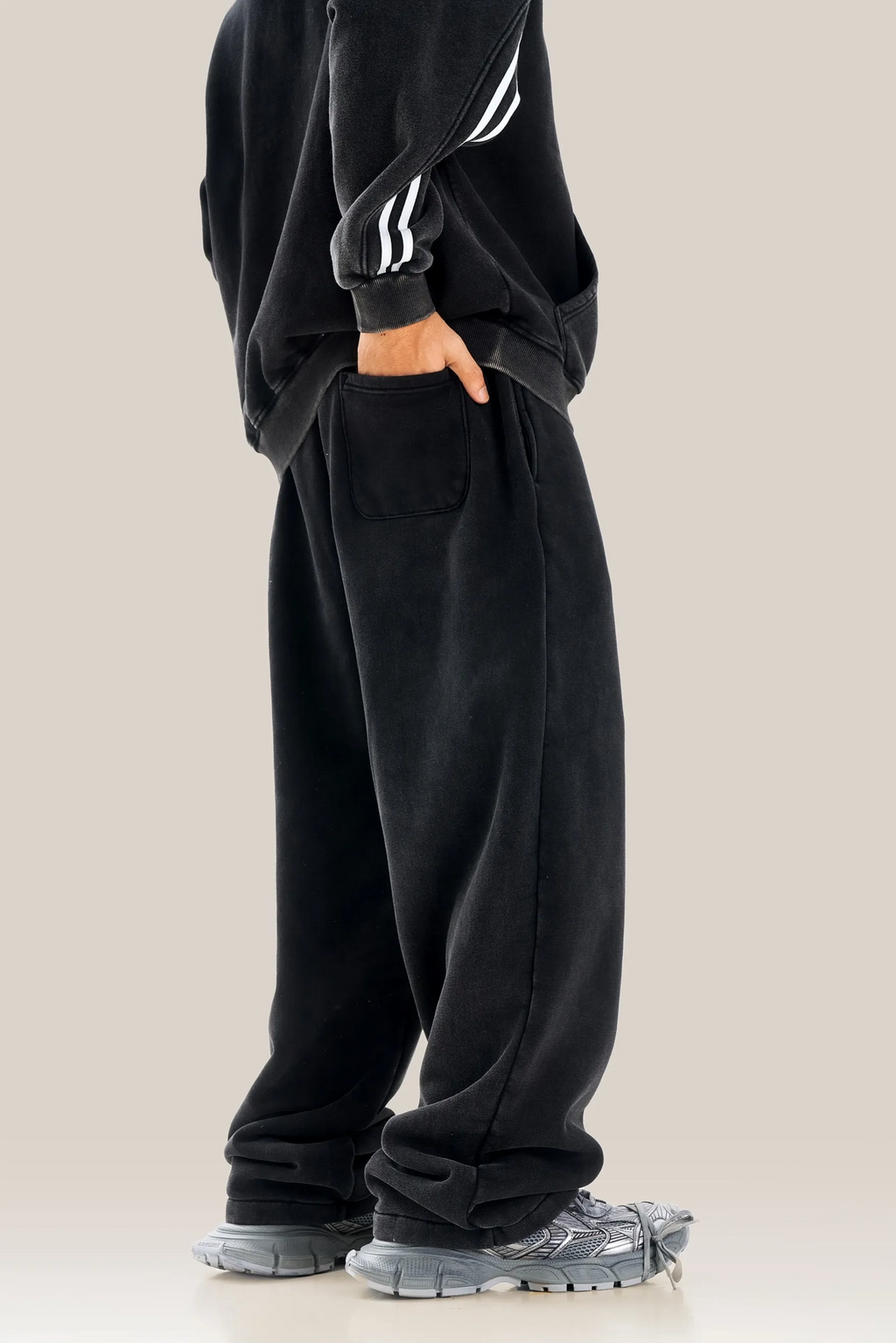 Person wearing a black outfit with white stripes on a beige background