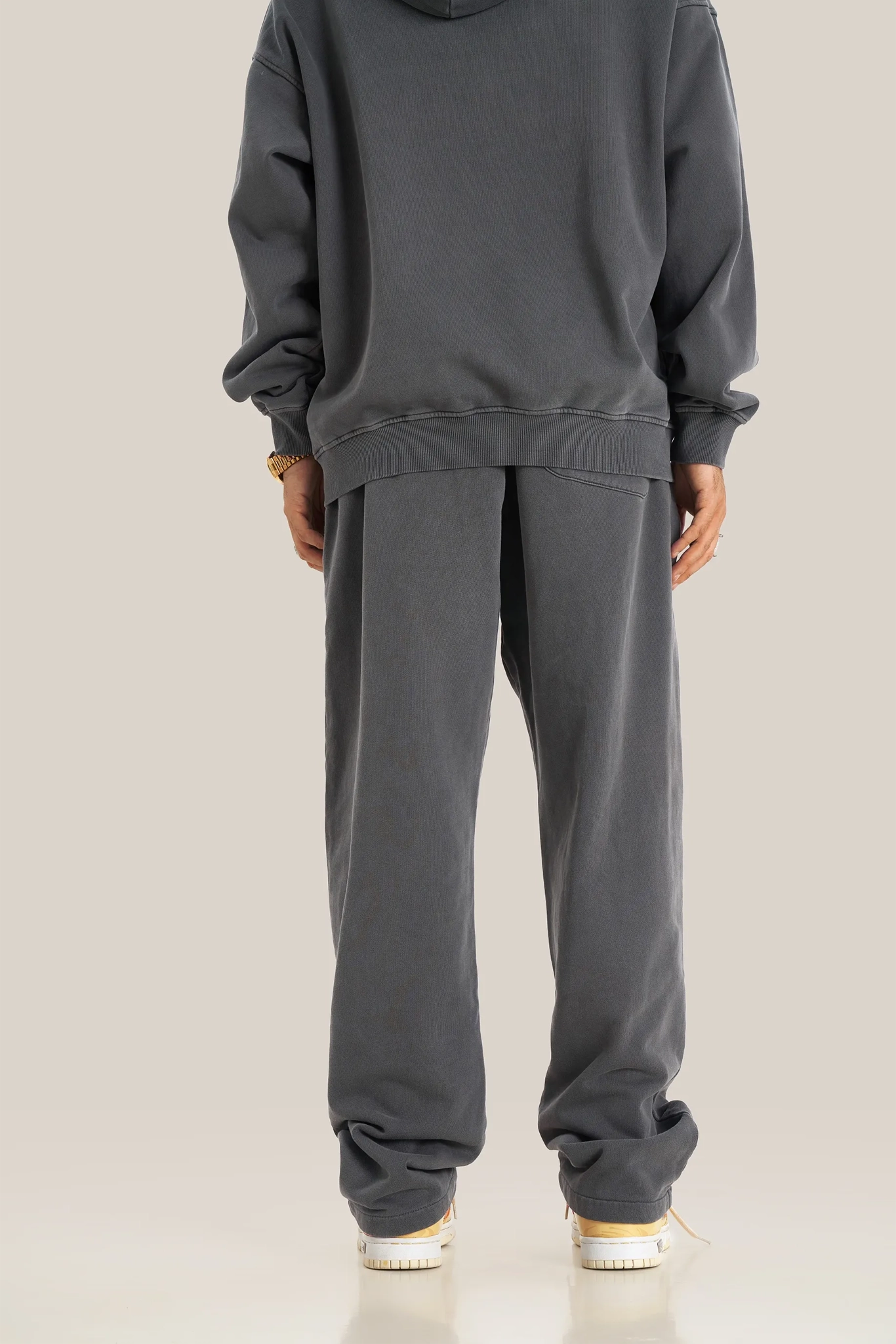 Person wearing a gray tracksuit on a beige background