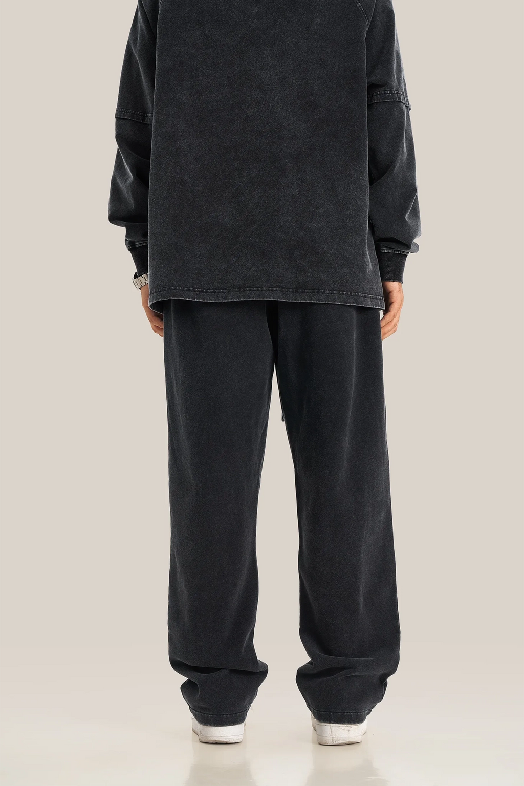 Person wearing a black outfit with wide-leg pants on a plain background