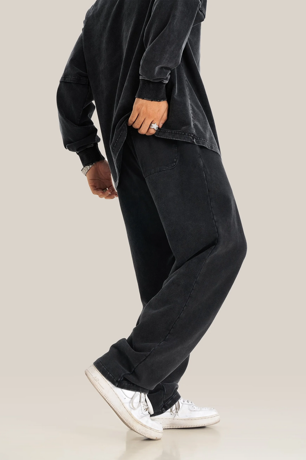 Person wearing a black outfit with white sneakers on a beige background