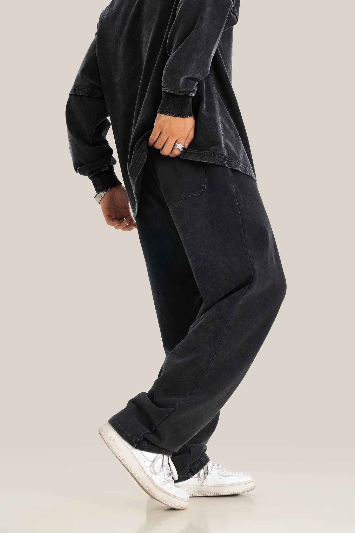 Person wearing a black outfit with white sneakers on a beige background