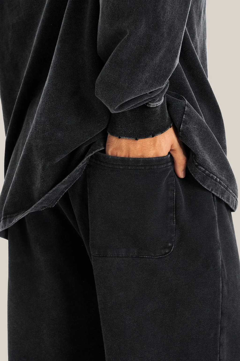 Person wearing a black oversized shirt and pants with a neutral background