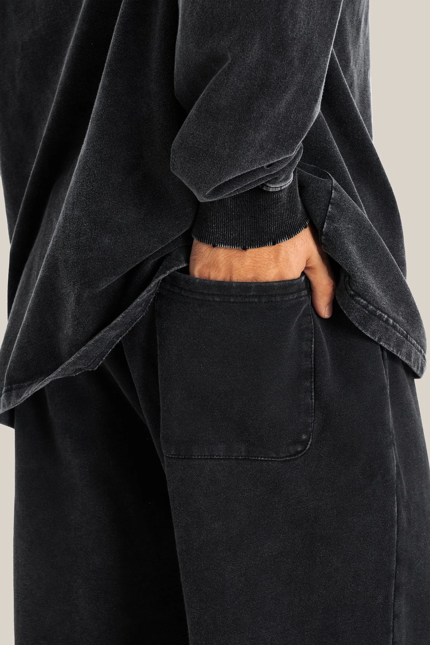 Person wearing a black oversized shirt and pants with a neutral background