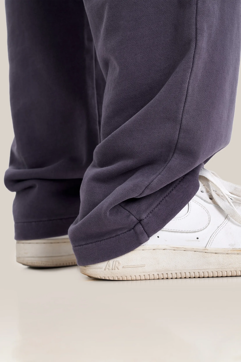 Navy blue pants with white sneakers on a light background