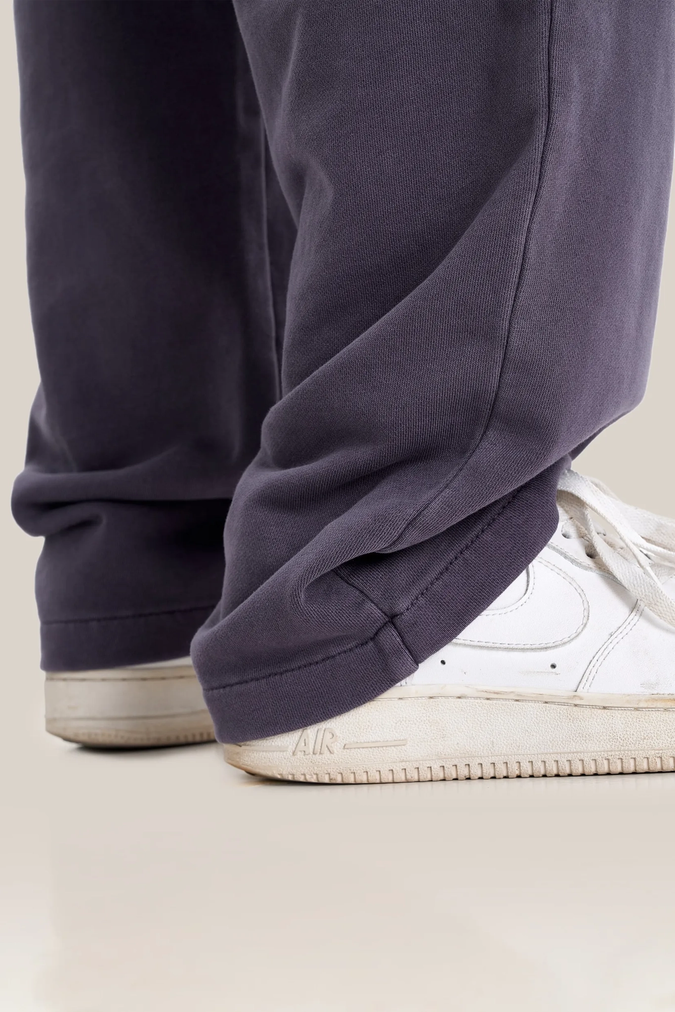 Navy blue pants with white sneakers on a light background