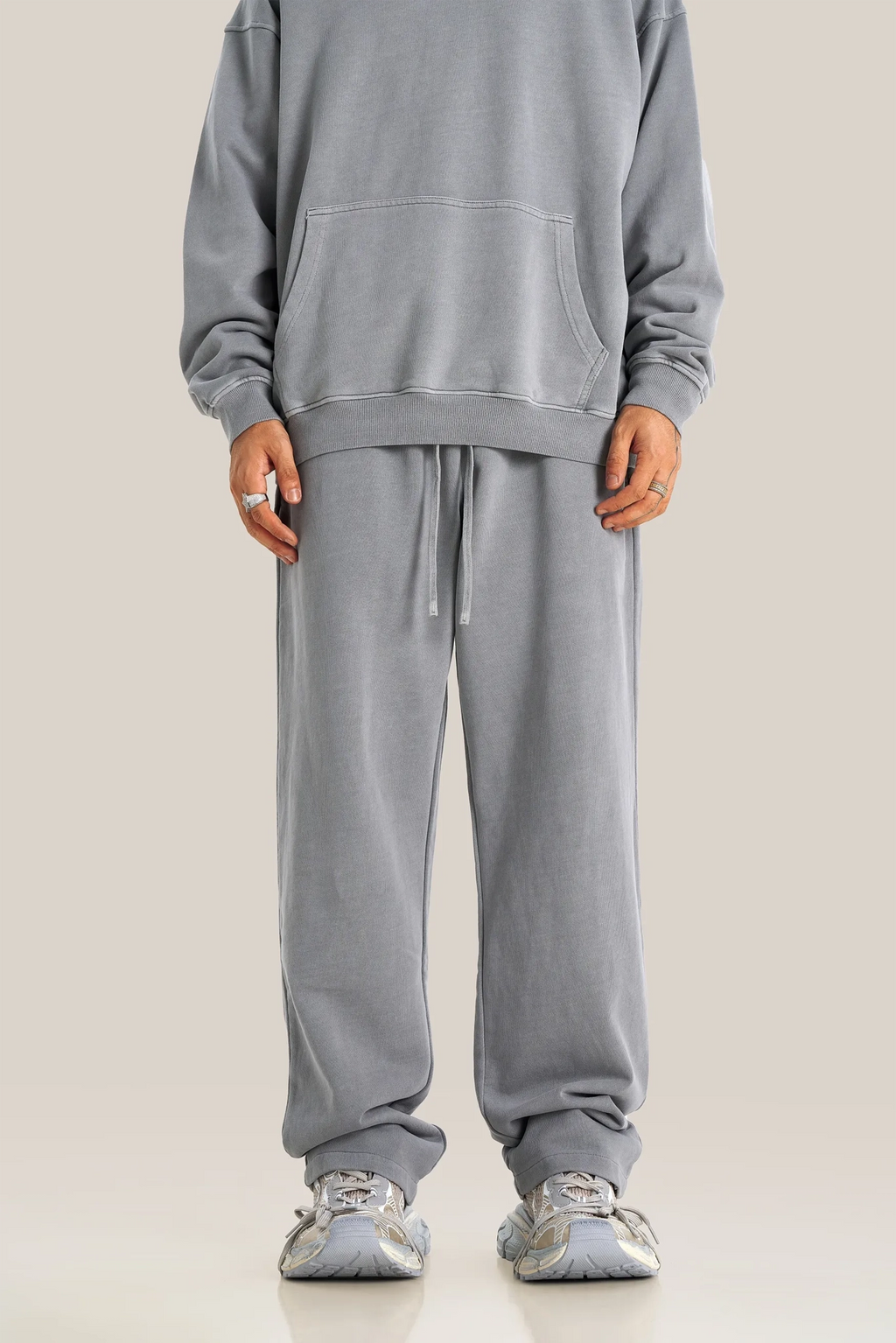 Person wearing a gray tracksuit on a plain background