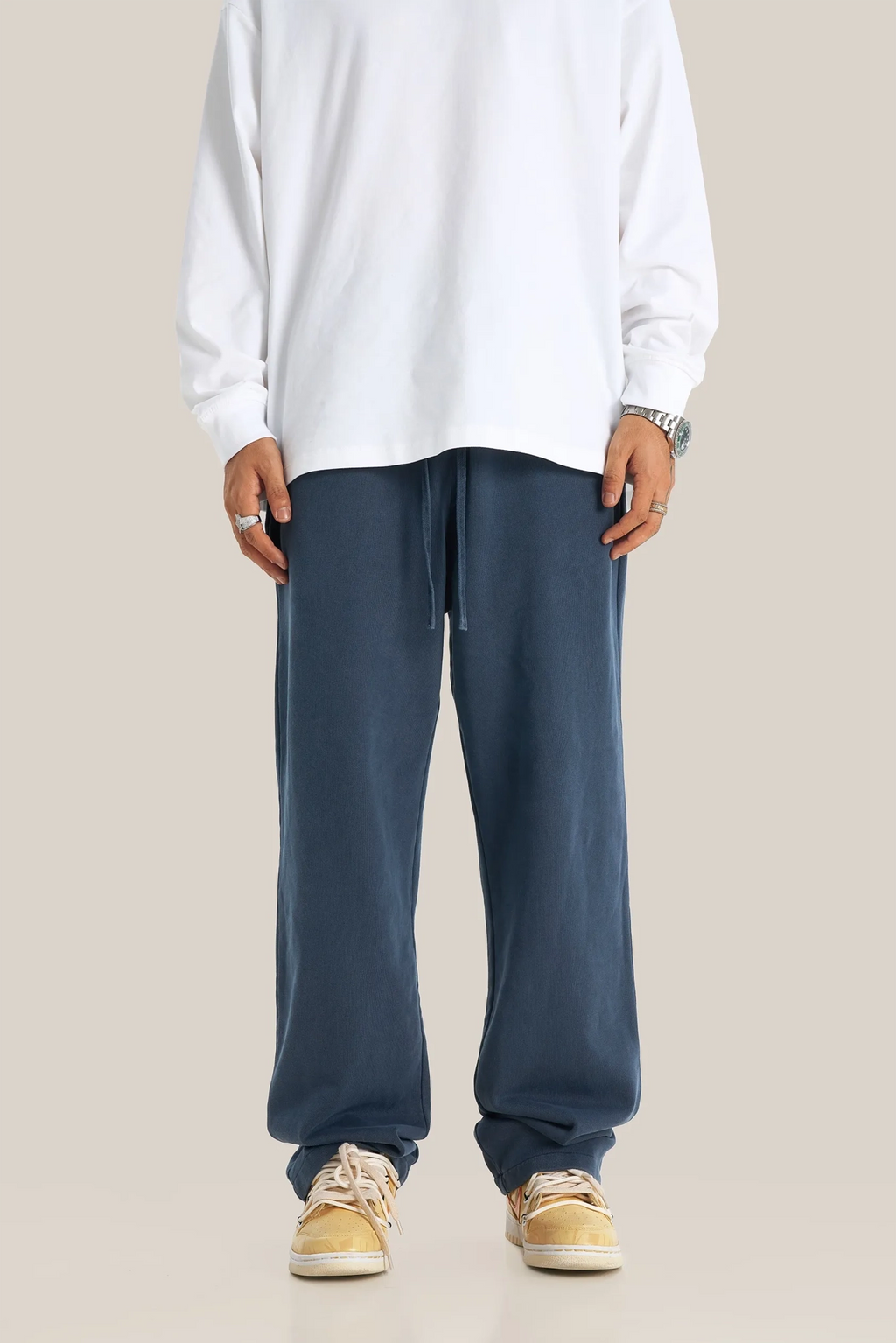 Person wearing a white sweatshirt and blue pants on a beige background
