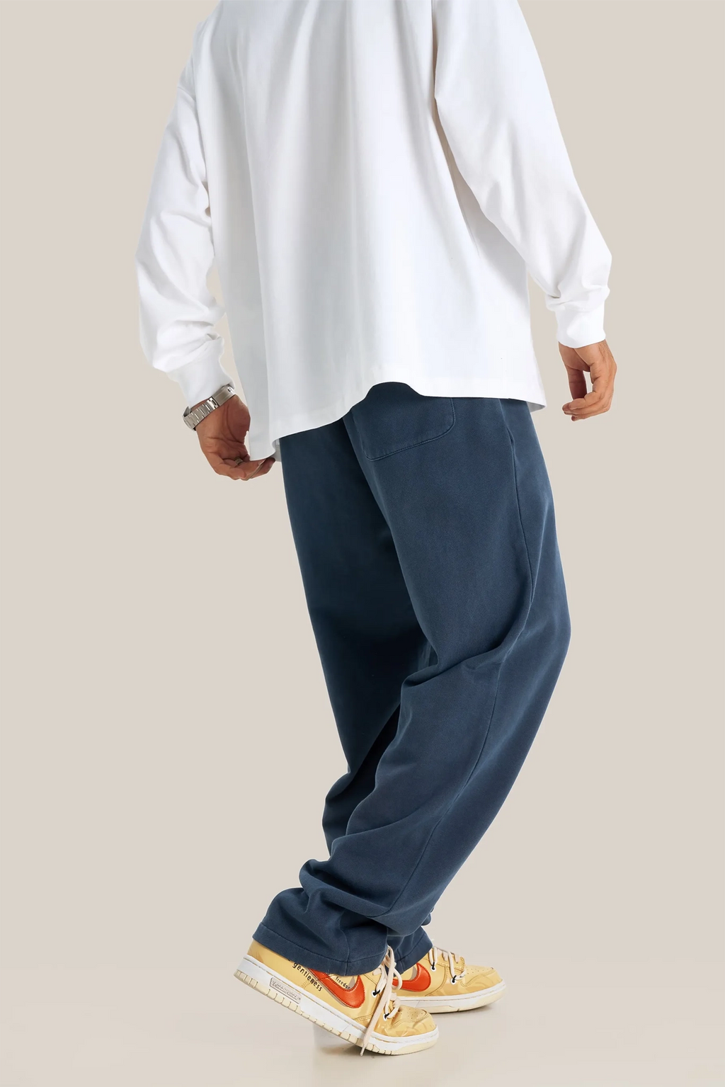Person wearing a white shirt and blue pants on a beige background