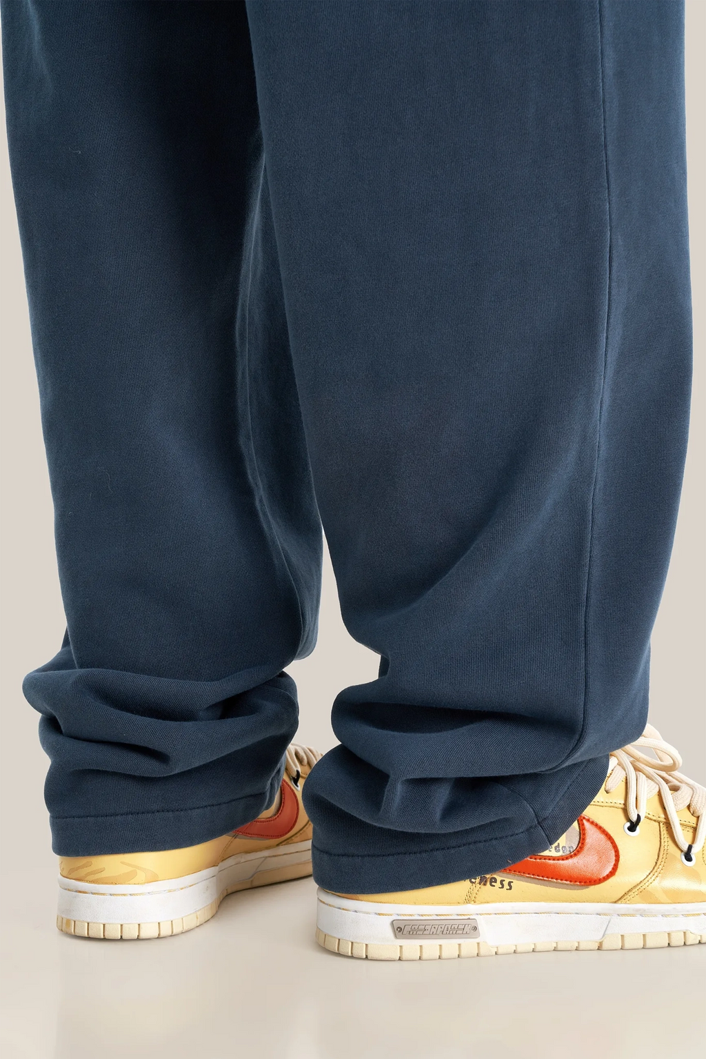 Navy blue pants worn with colorful sneakers on a neutral background