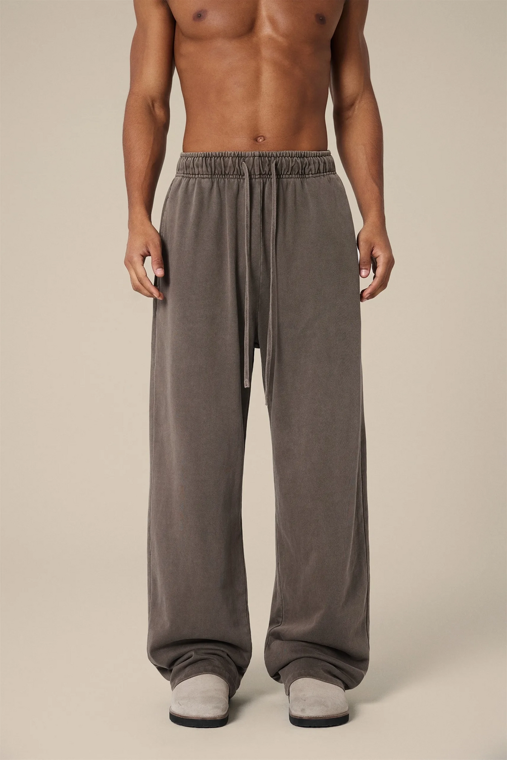 Man wearing brown lounge pants on a beige background