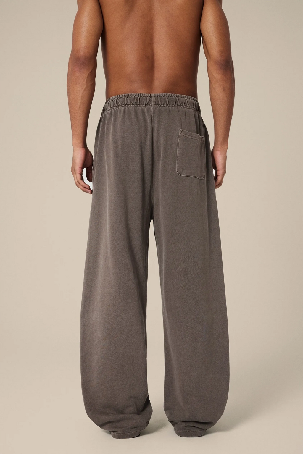 Brown wide-leg pants worn by a person on a beige background