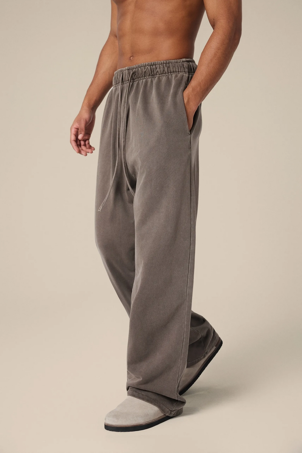 Person wearing gray sweatpants on a beige background