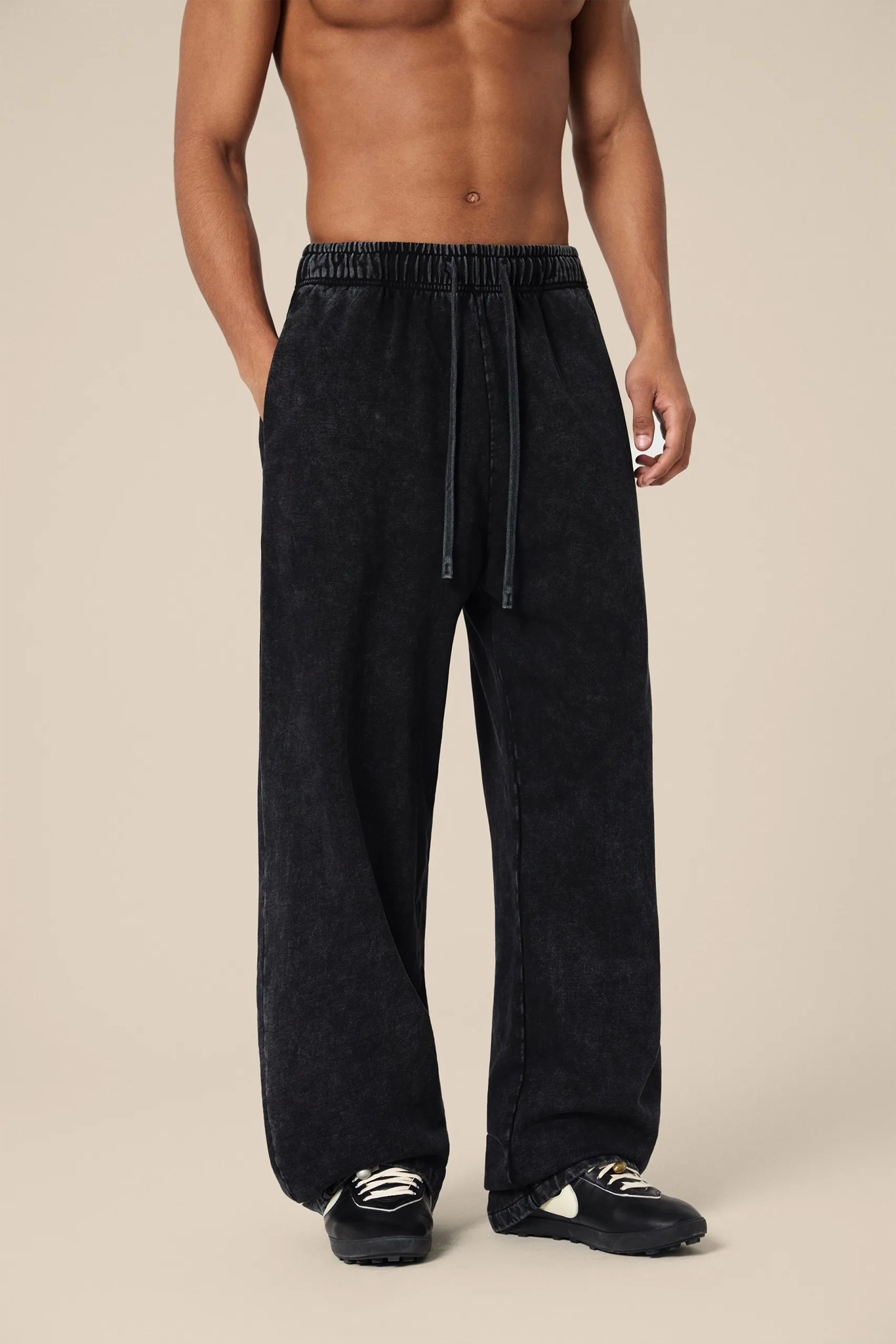 Person wearing black pants on a beige background