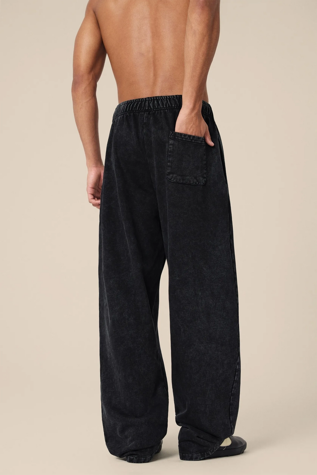 Person wearing black wide-leg pants on a beige background