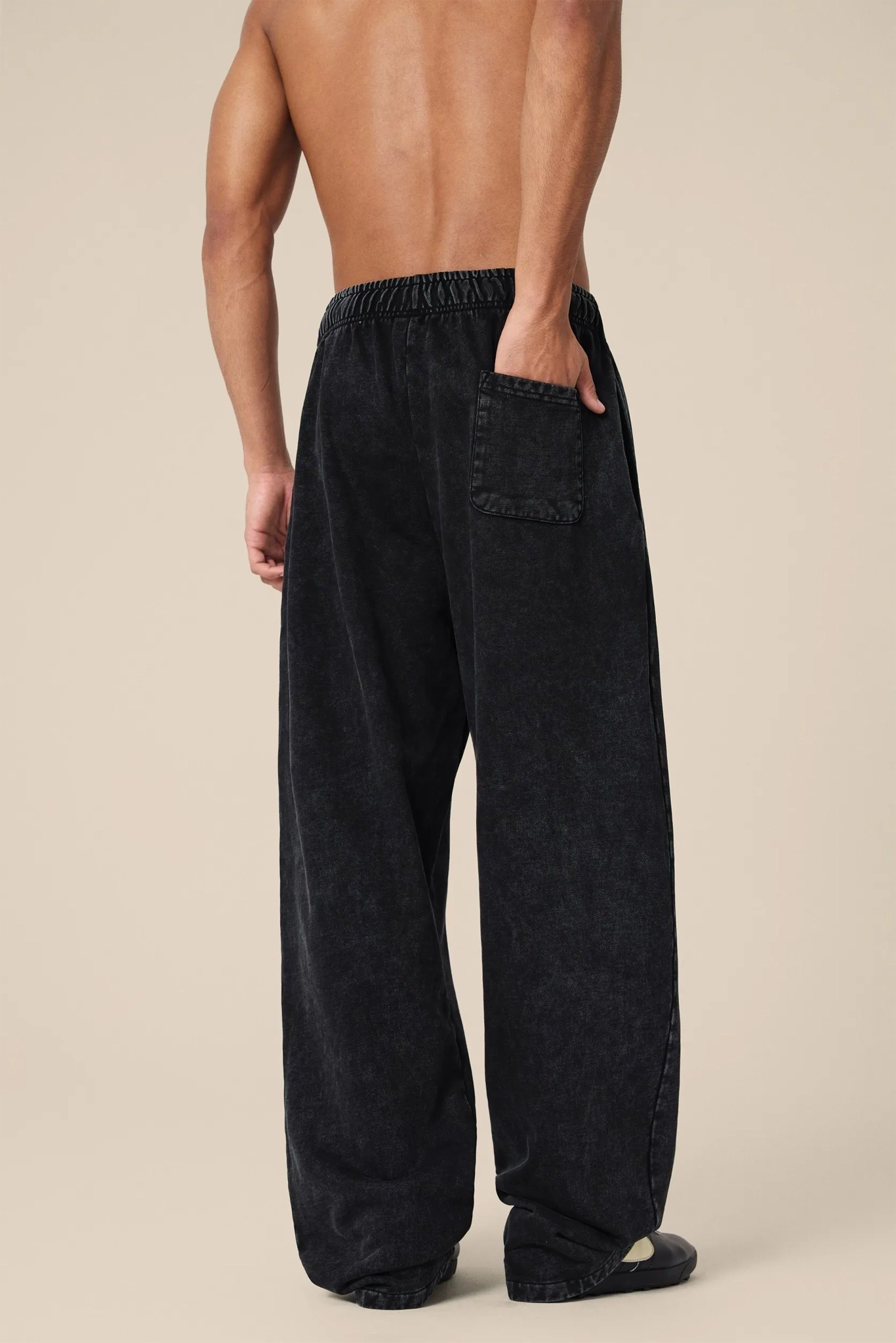 Person wearing black wide-leg pants on a beige background