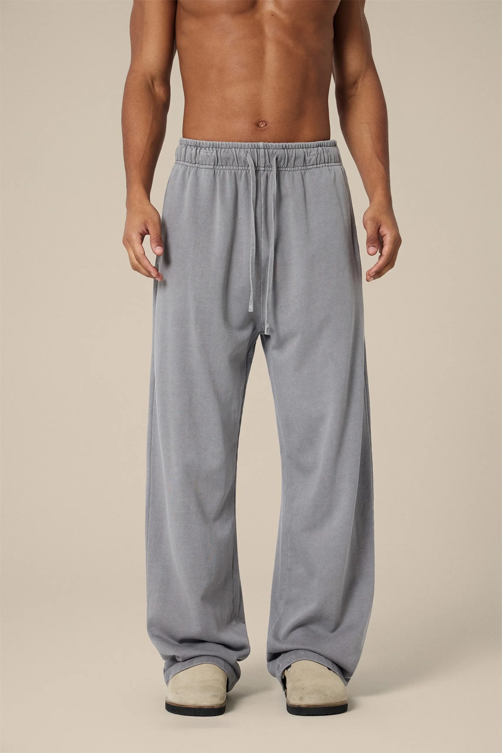 Person wearing gray sweatpants on a beige background