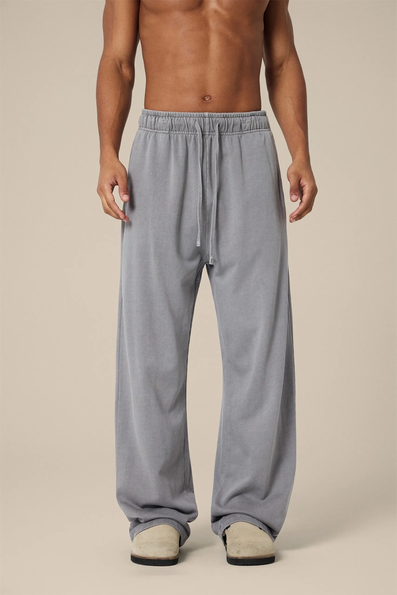 Person wearing gray sweatpants on a beige background