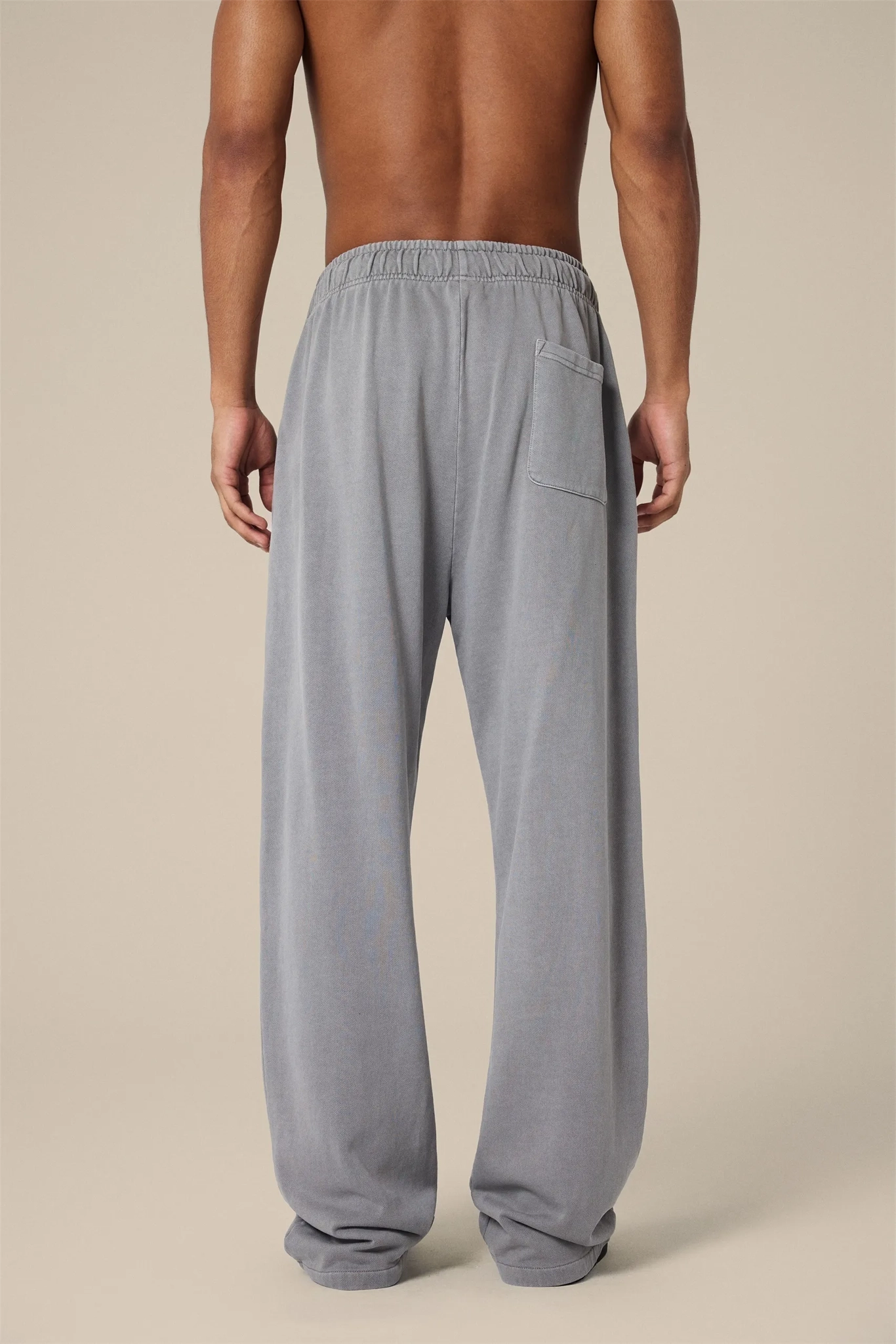 Gray sweatpants worn by a person on a beige background
