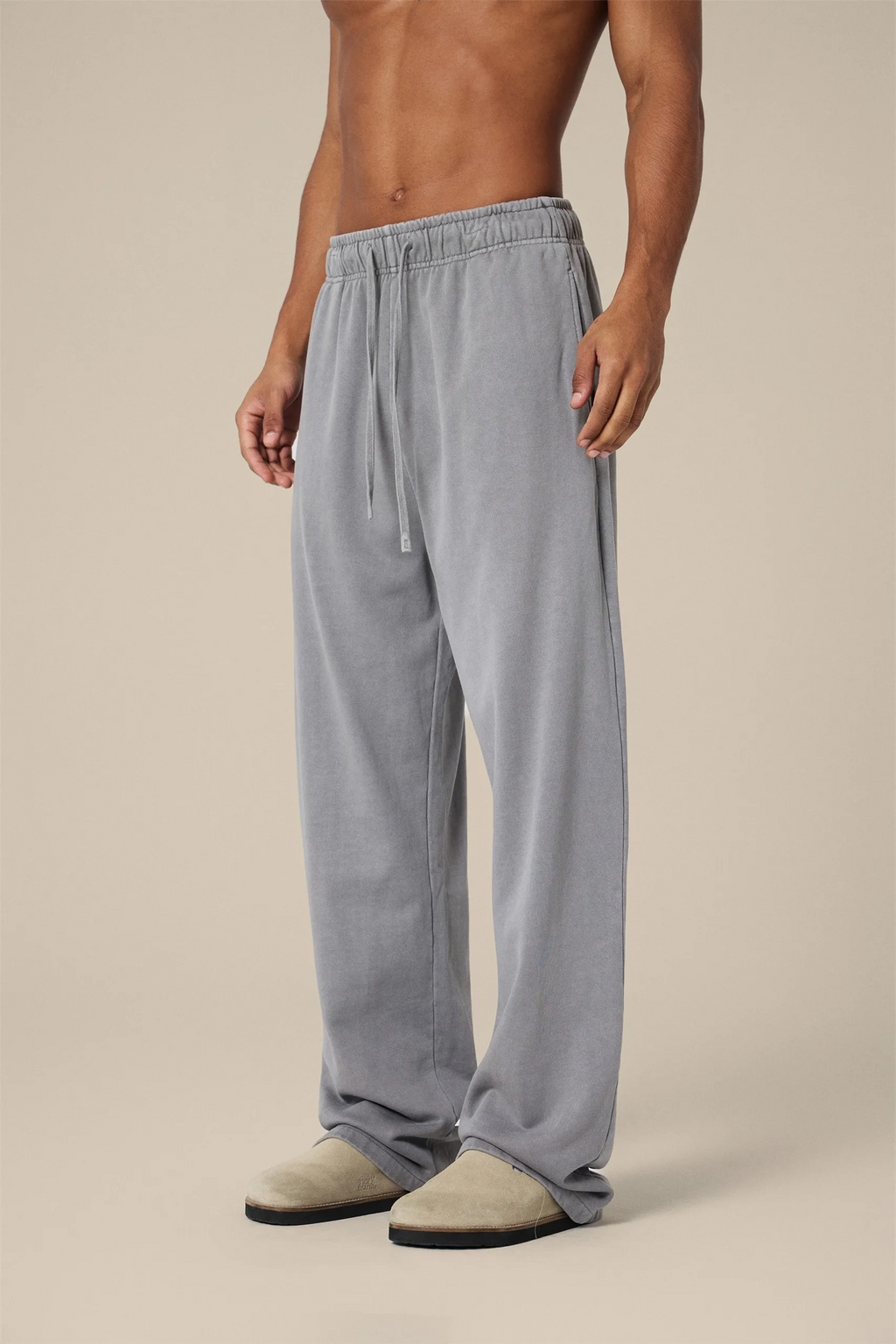 Person wearing gray pajama pants on a beige background