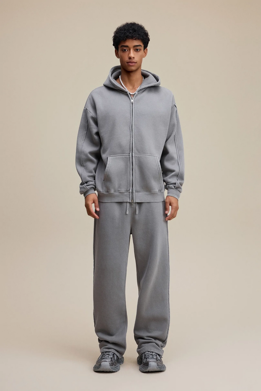 Person wearing a gray tracksuit on a beige background