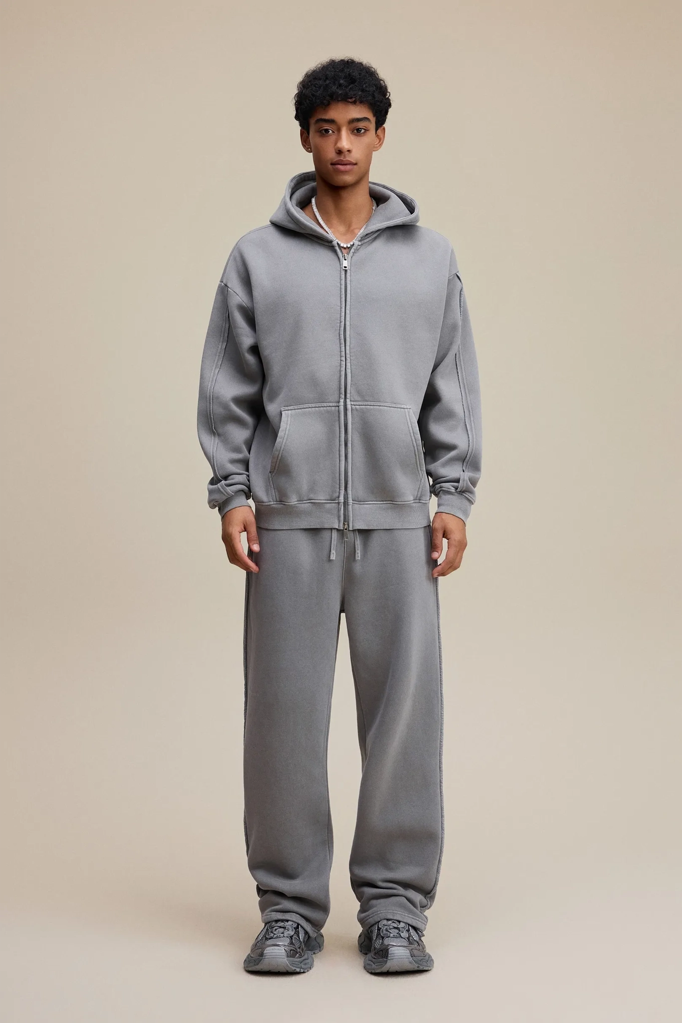 Person wearing a gray tracksuit on a beige background