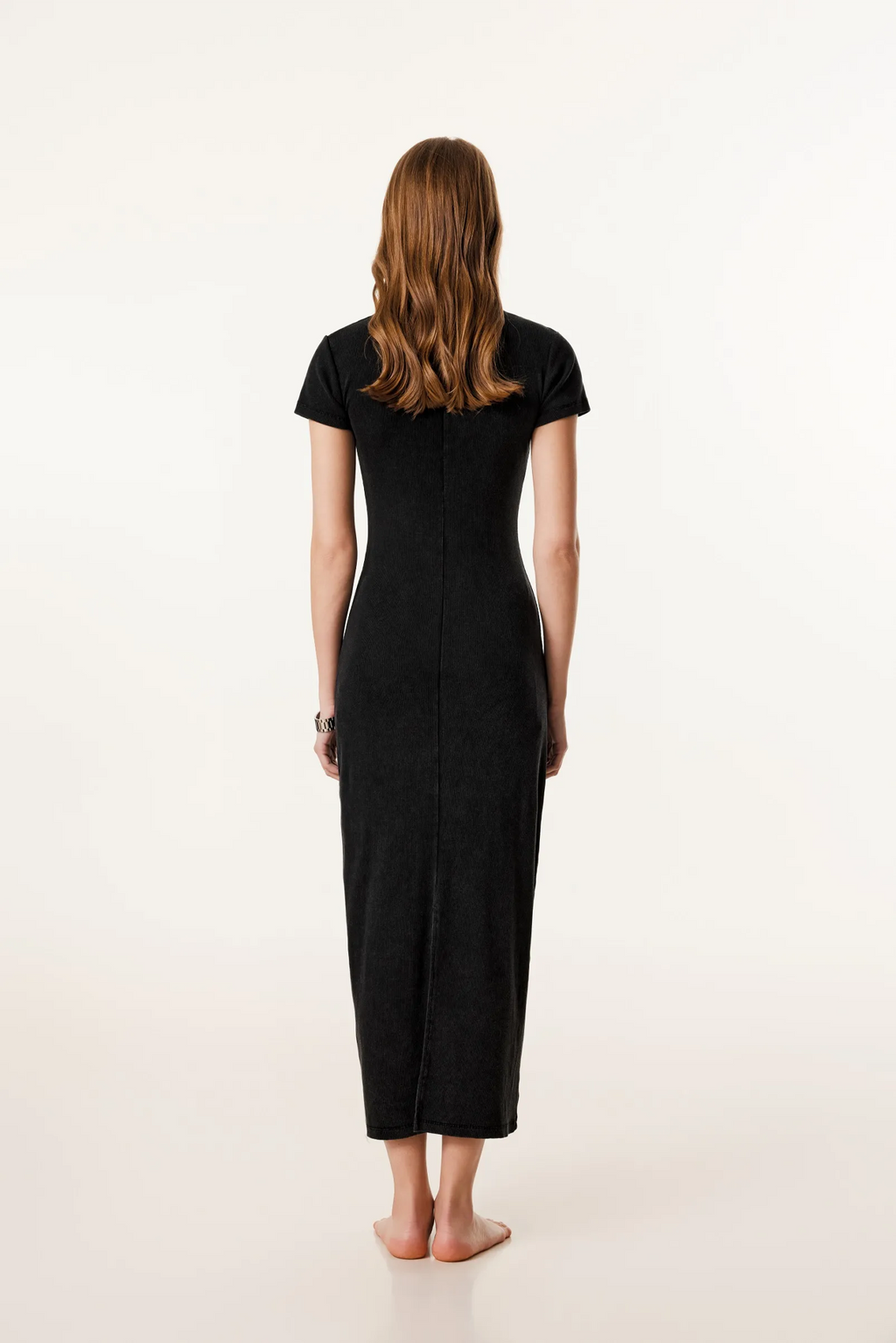 Woman wearing a black dress standing against a white background