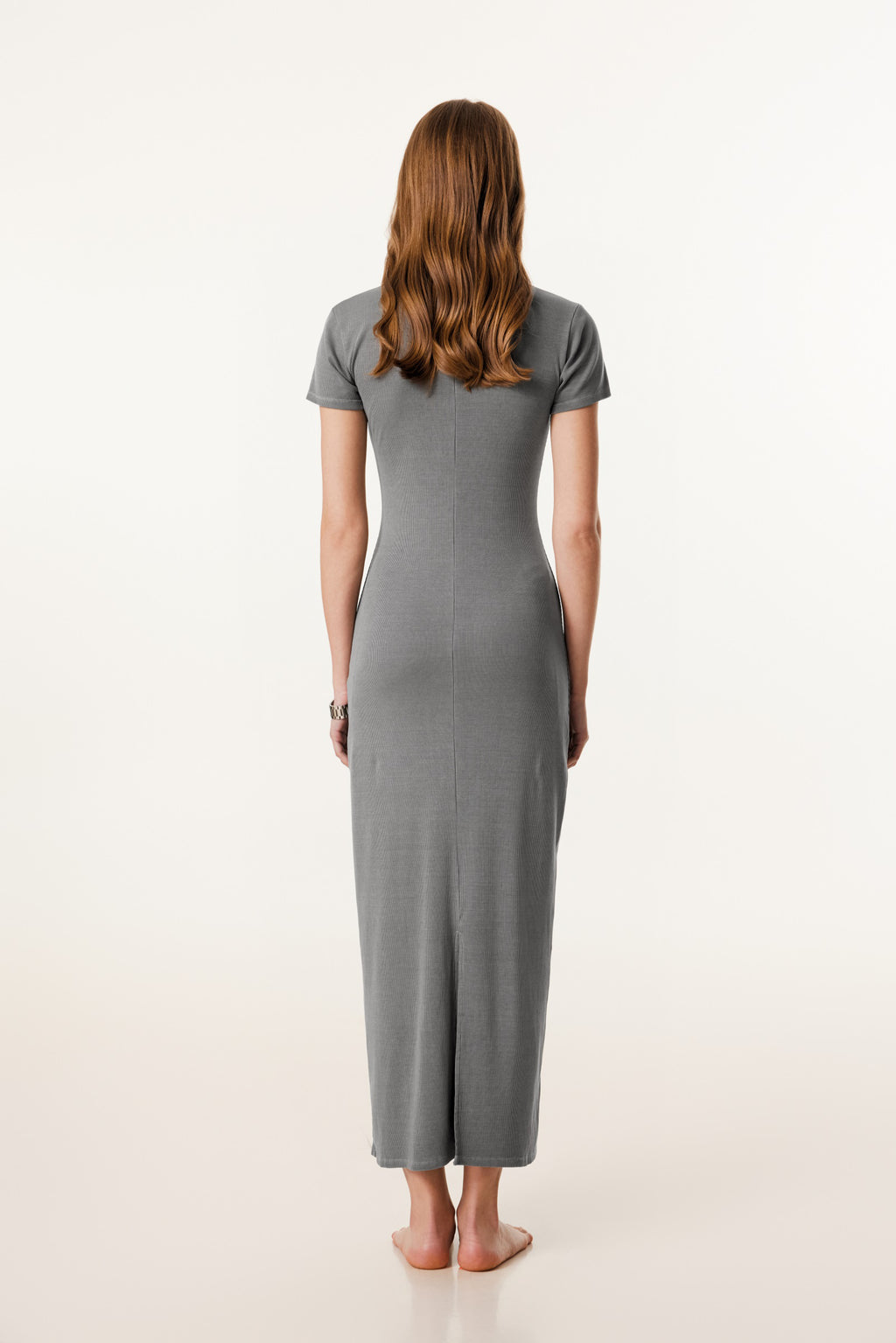Woman wearing a gray dress standing against a white background