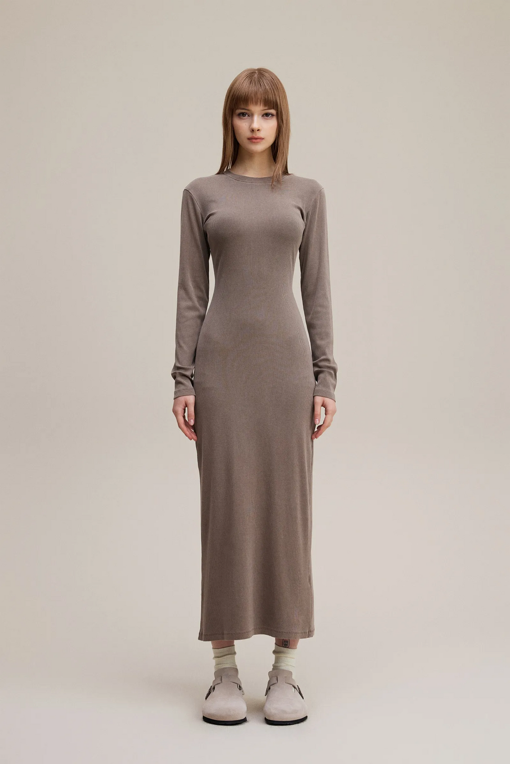 Woman wearing a long brown dress on a plain background