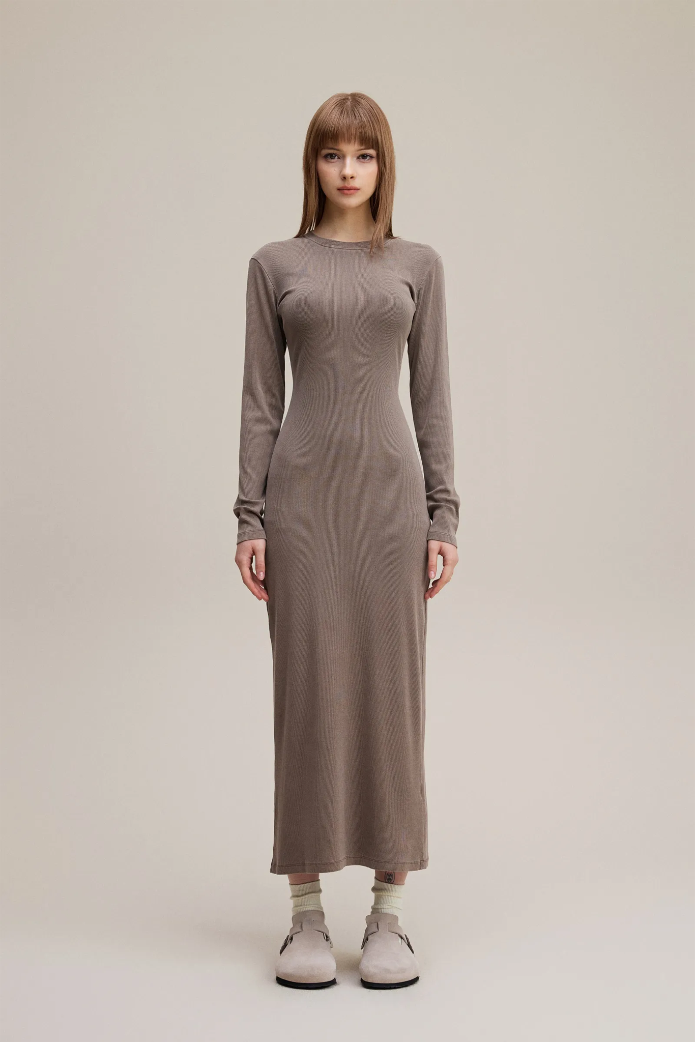 Woman wearing a long brown dress on a plain background