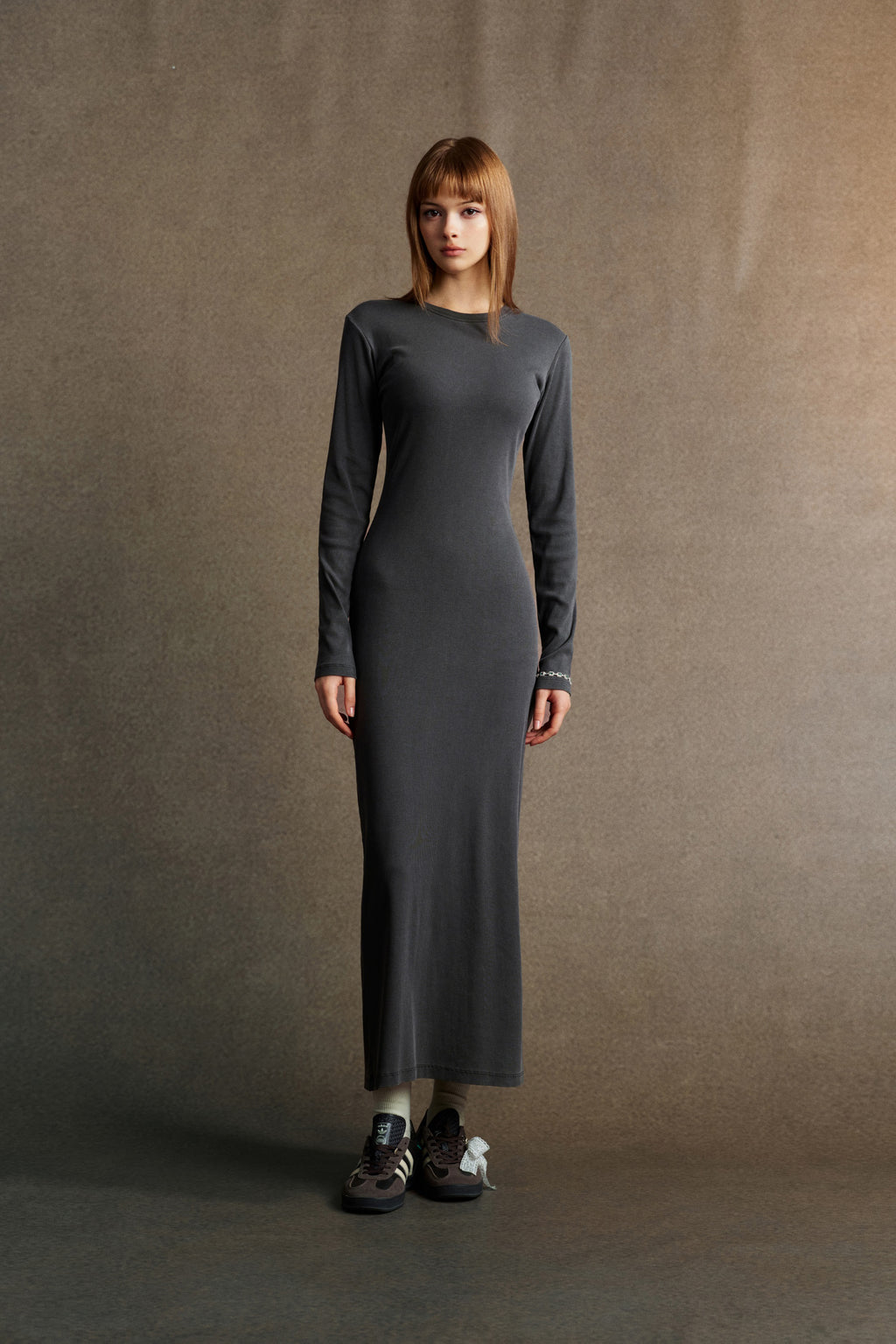 Woman wearing a gray long-sleeve dress against a brown background
