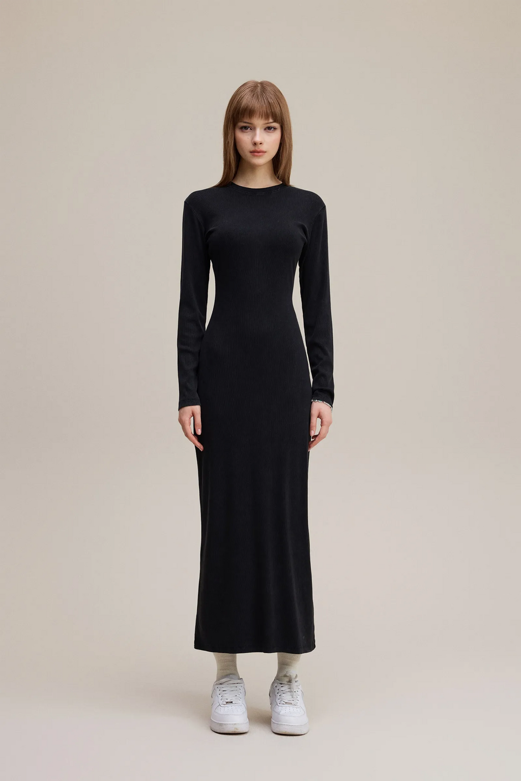 Woman wearing a black long-sleeve dress on a beige background