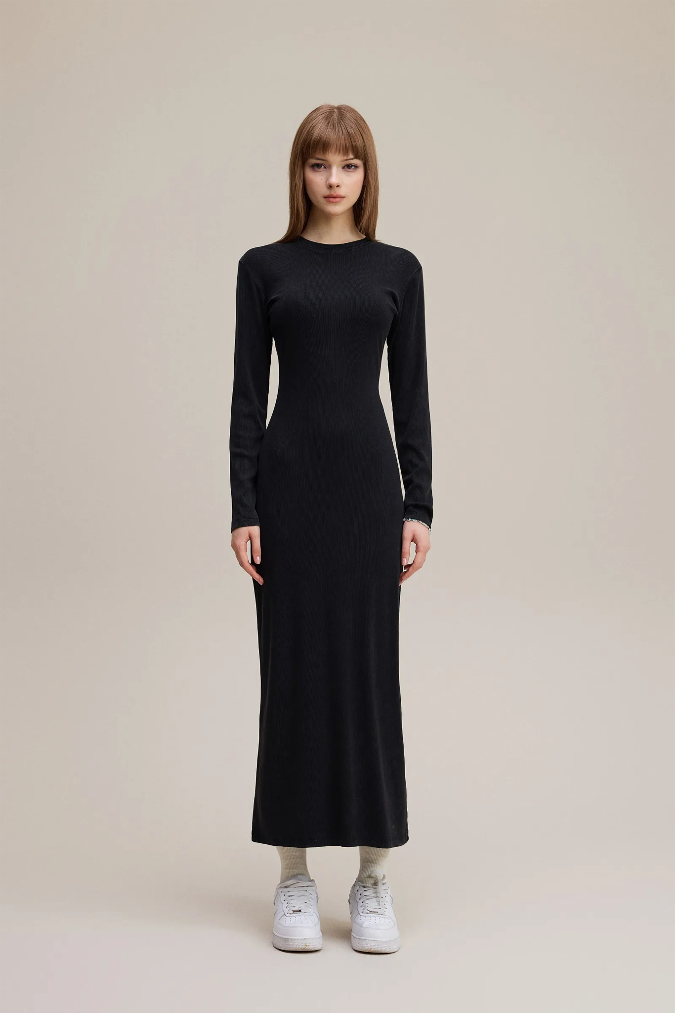 Woman wearing a black long-sleeve dress on a beige background