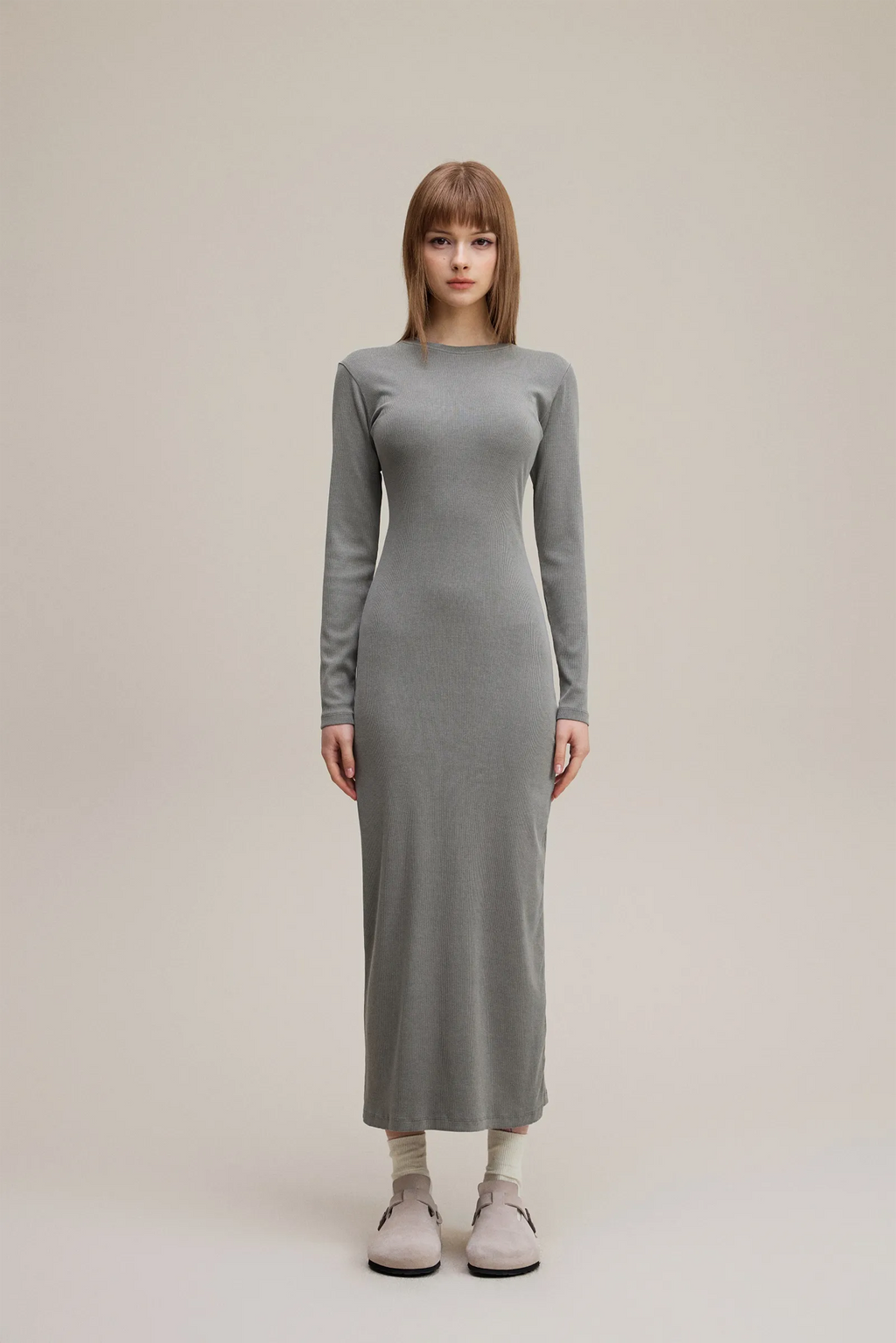 Woman wearing a long gray dress on a plain background