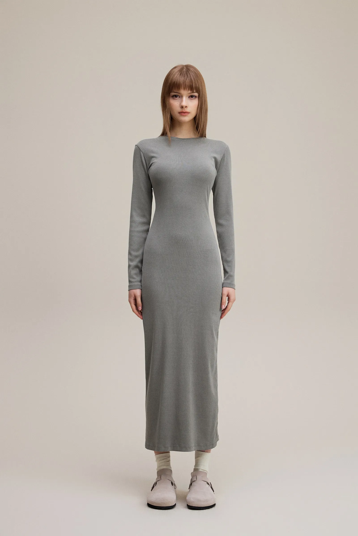 Woman wearing a long gray dress on a plain background
