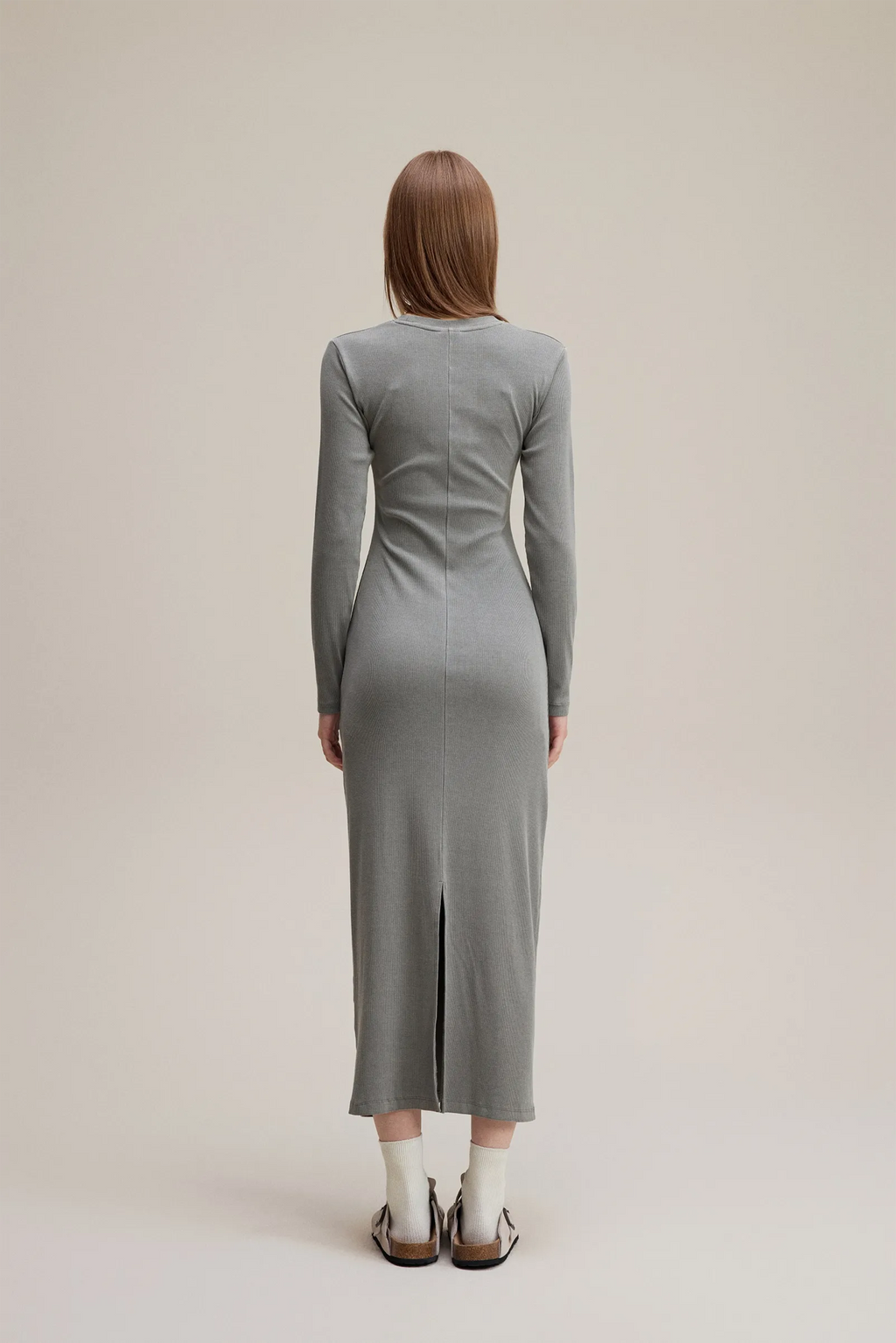 Person wearing a gray dress standing against a plain background