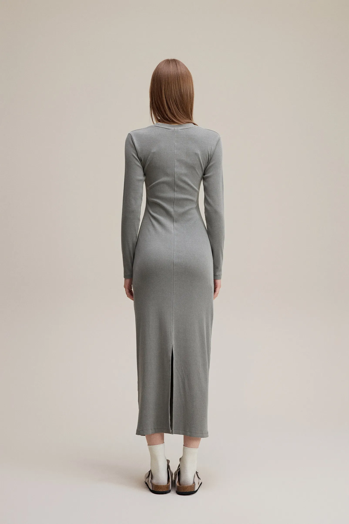 Person wearing a gray dress standing against a plain background