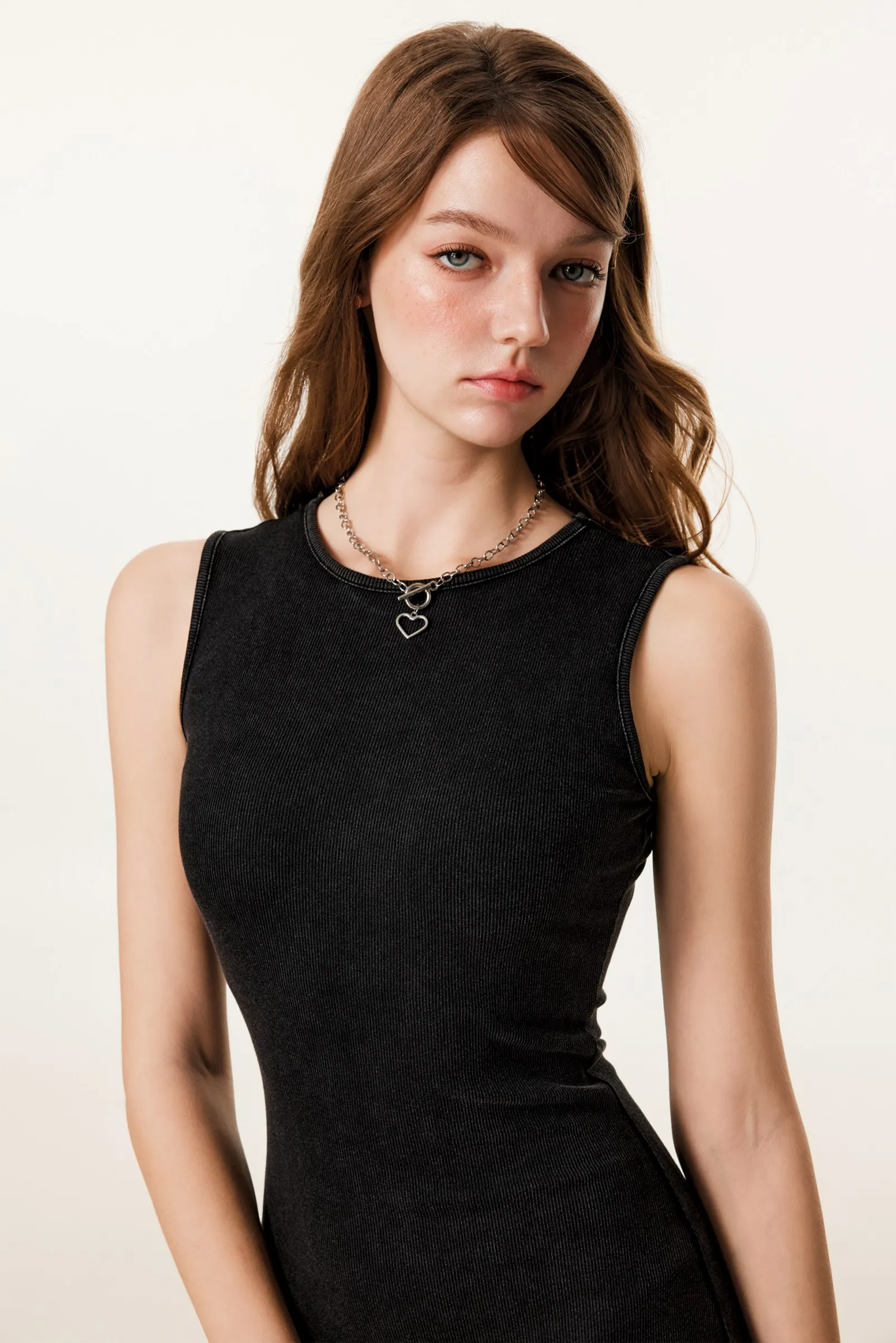 Woman wearing a black sleeveless dress with a plain background