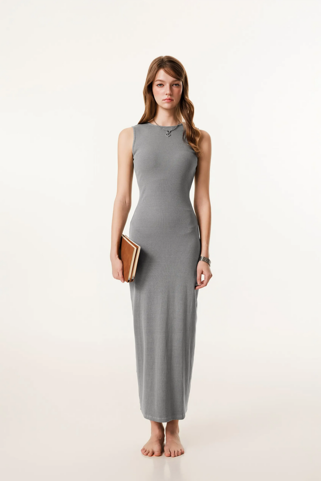 Woman wearing a gray sleeveless dress holding a clutch on a white background