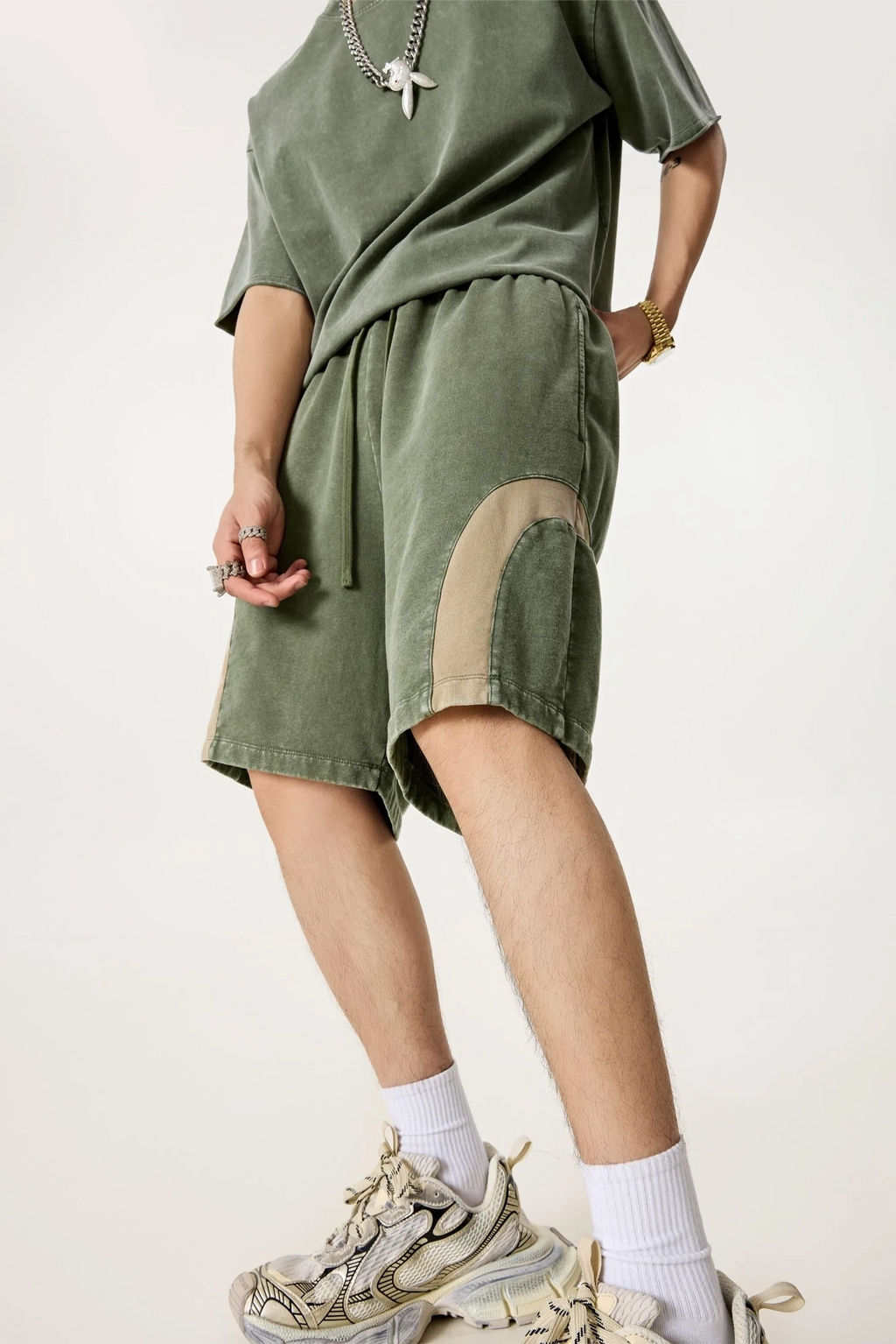 Person wearing an olive green outfit with shorts and a top on a white background