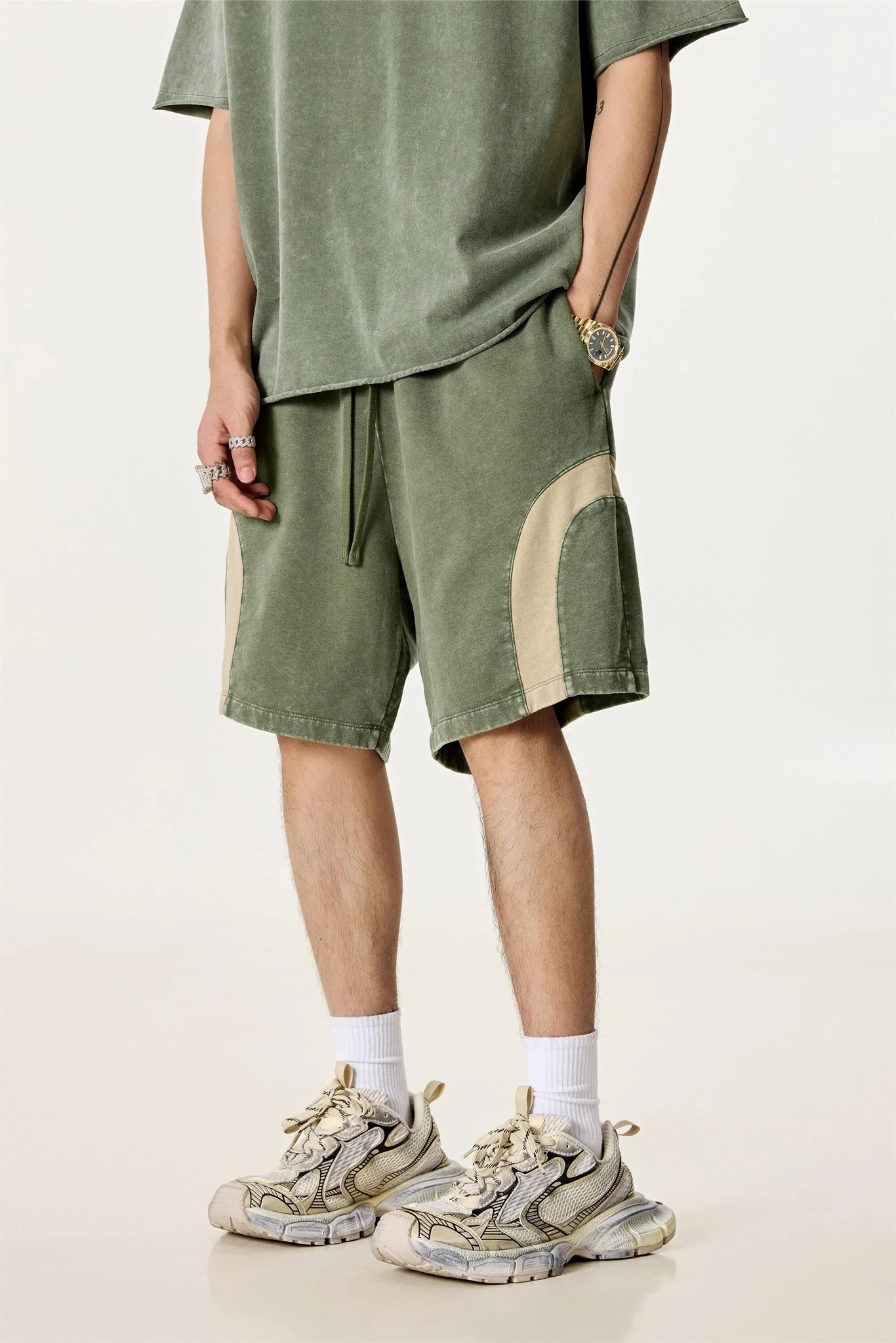 Person wearing a green outfit with shorts and sneakers on a plain background
