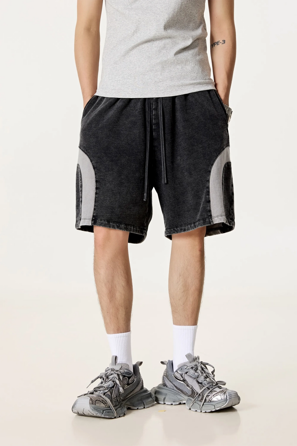 Person wearing black shorts with gray accents on a white background