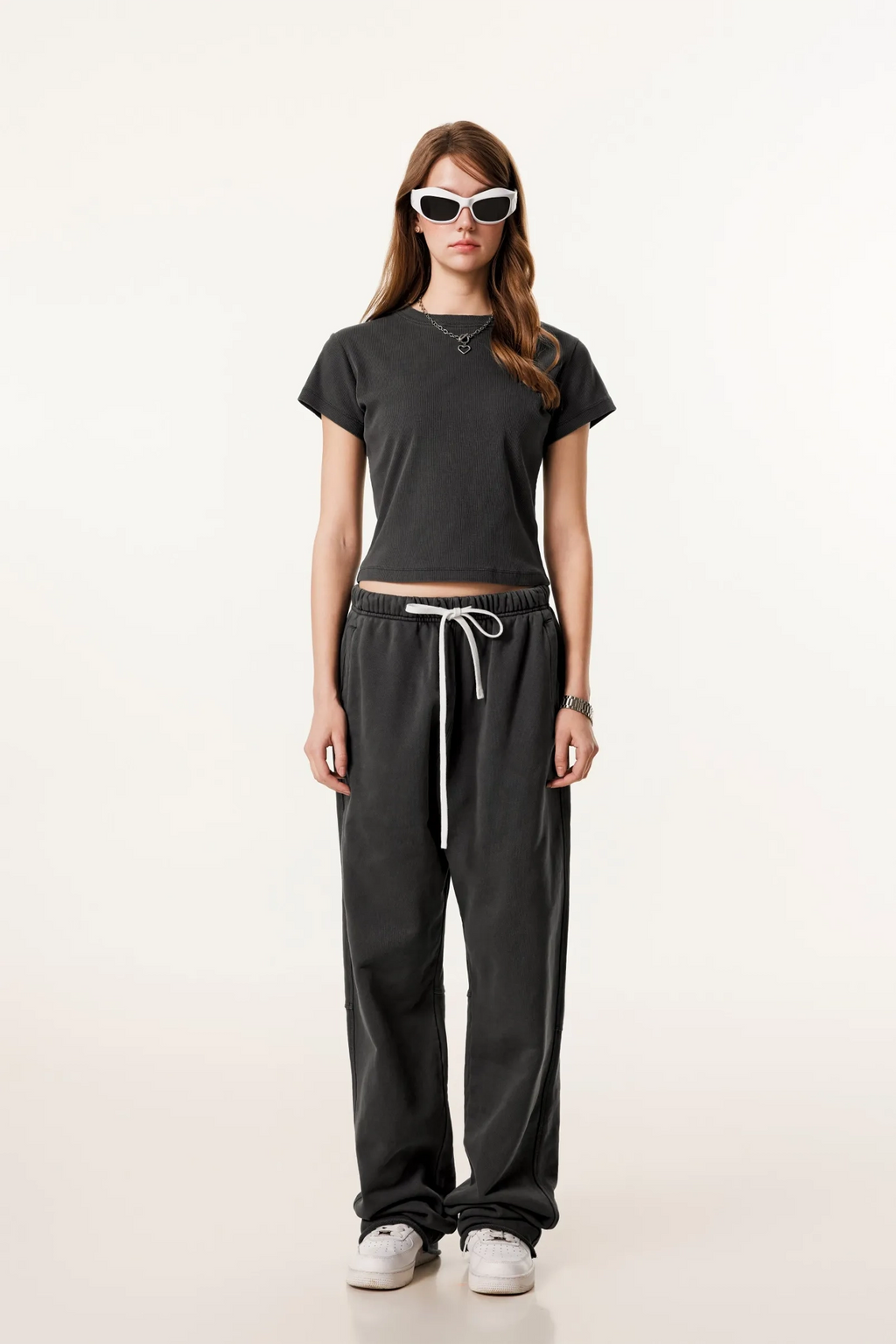 Person wearing a black t-shirt and black pants with white drawstring on a white background