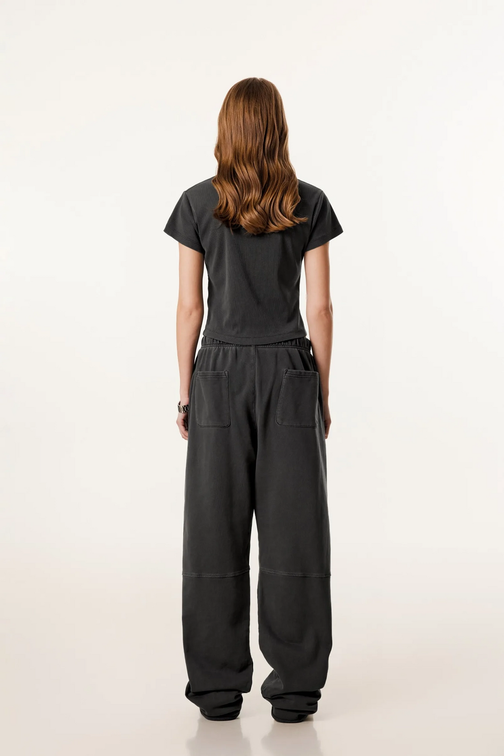 Person wearing a black outfit with wide-leg pants on a white background