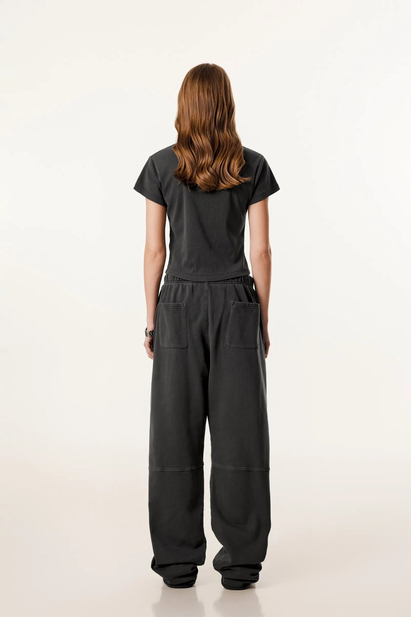Person wearing a black outfit with wide-leg pants on a white background