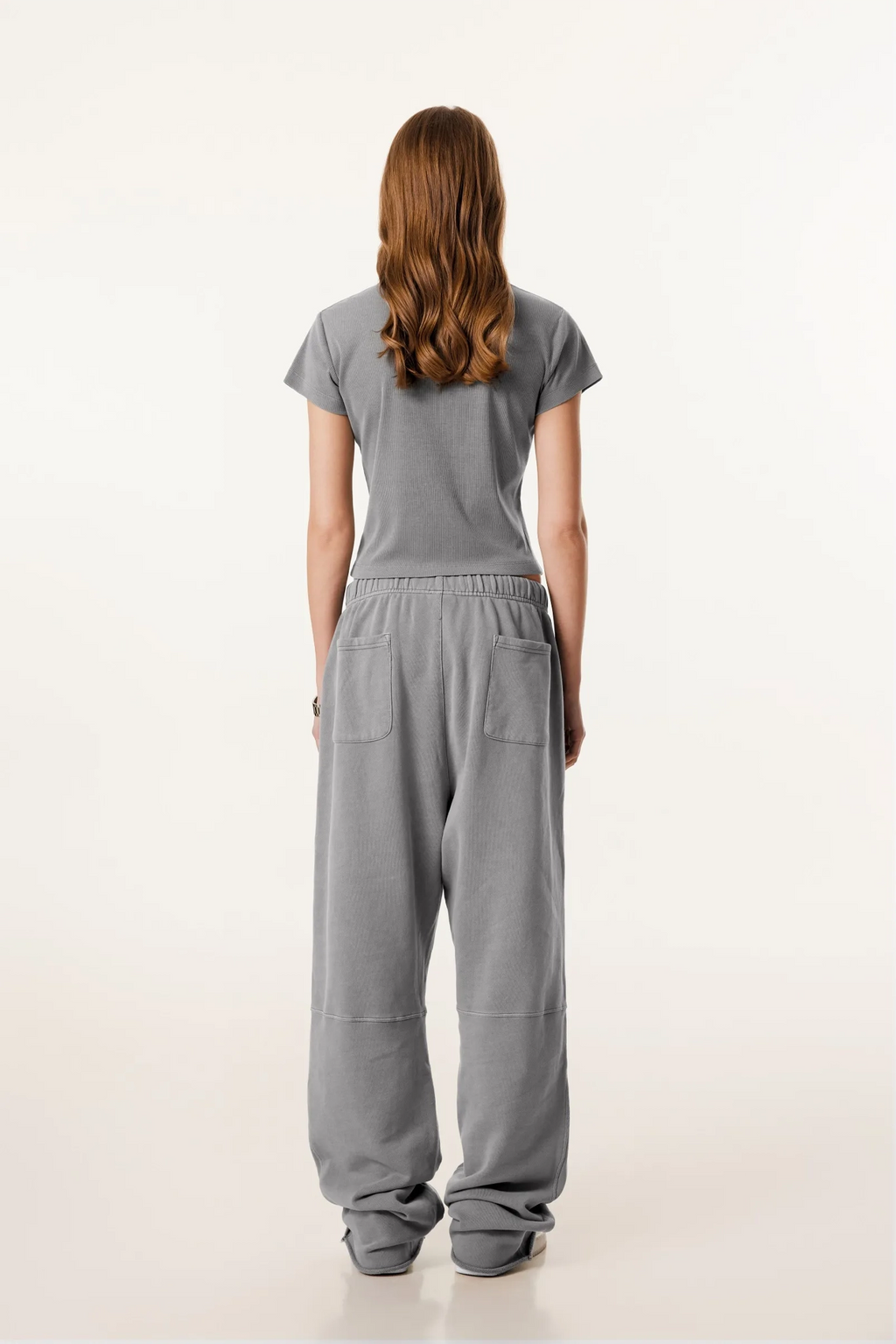 Person wearing a gray outfit with a plain background