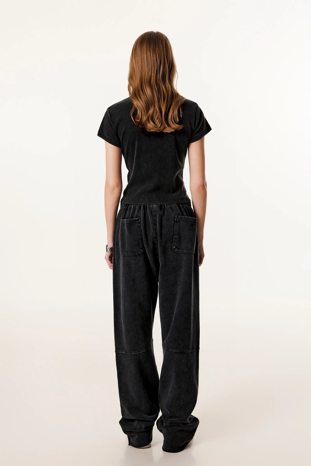 Person wearing a black outfit with wide-leg pants on a white background