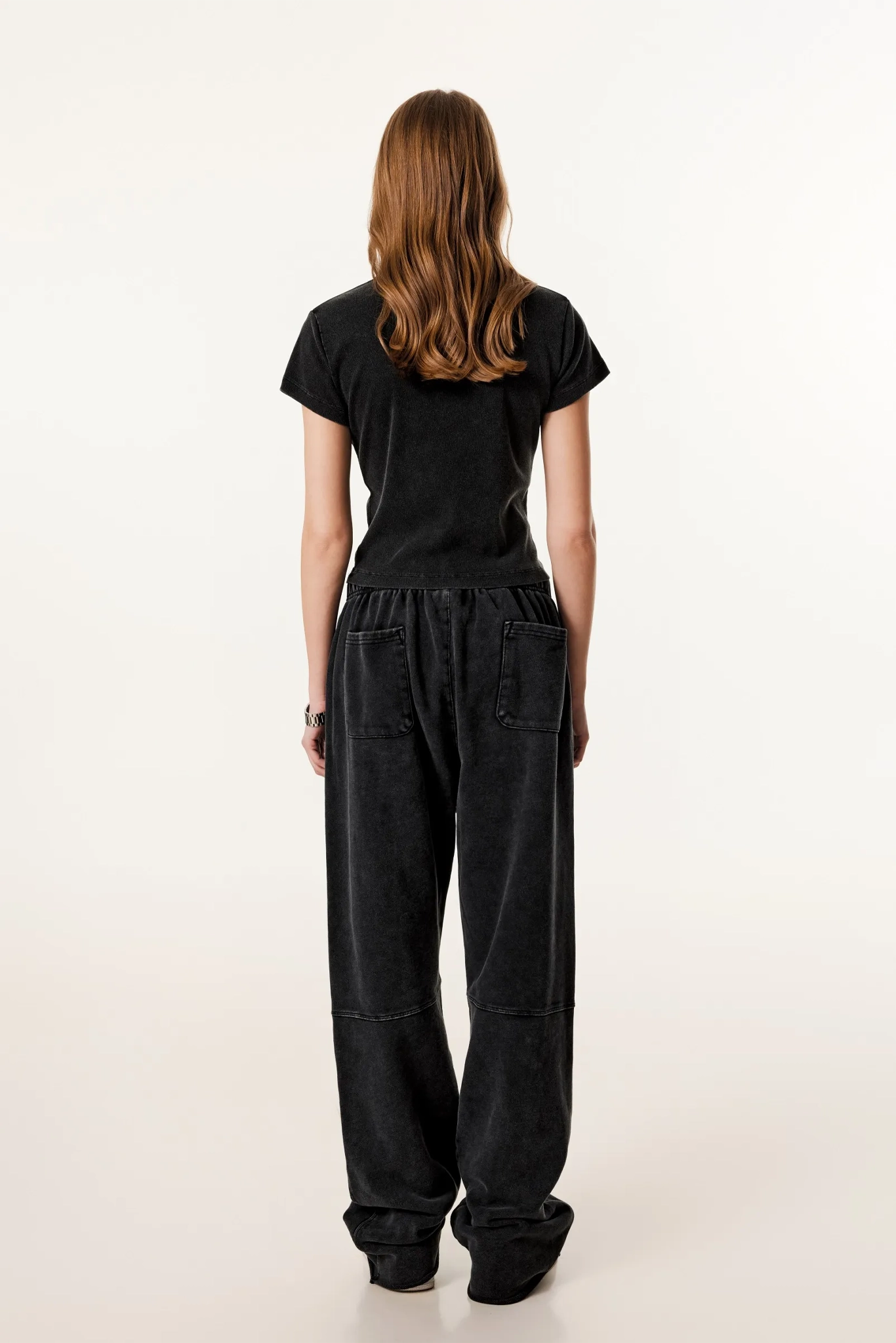 Person wearing a black outfit with wide-leg pants on a white background