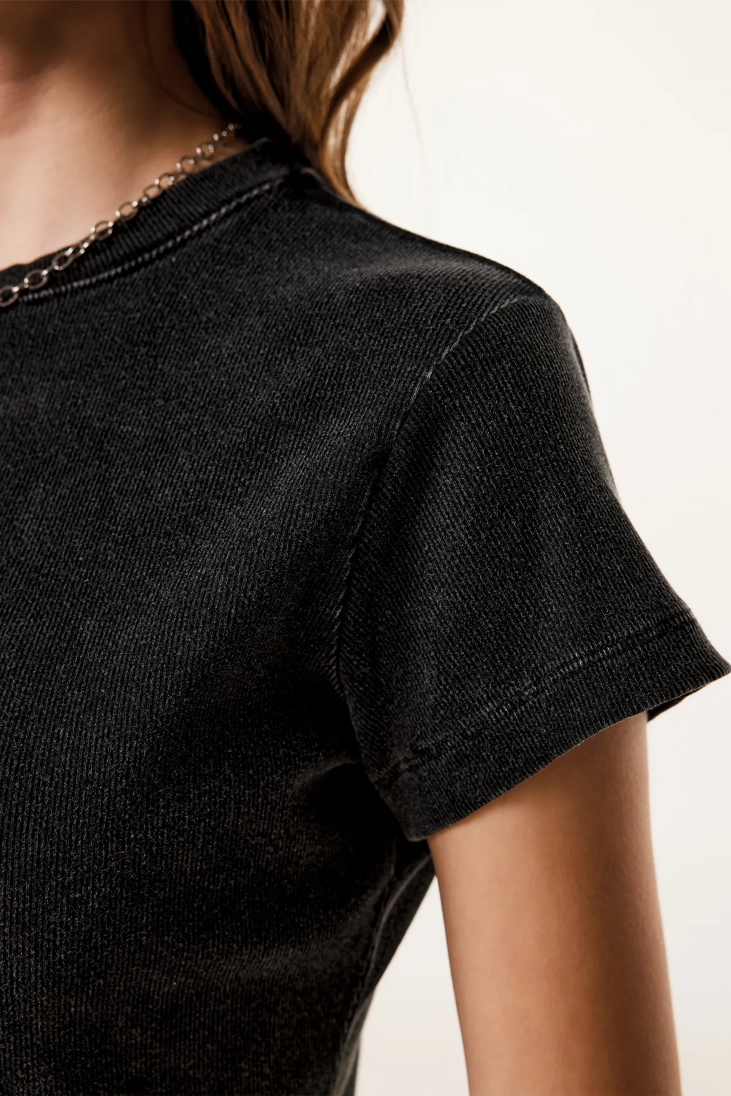 Close-up of a person wearing a black t-shirt with a blurred background