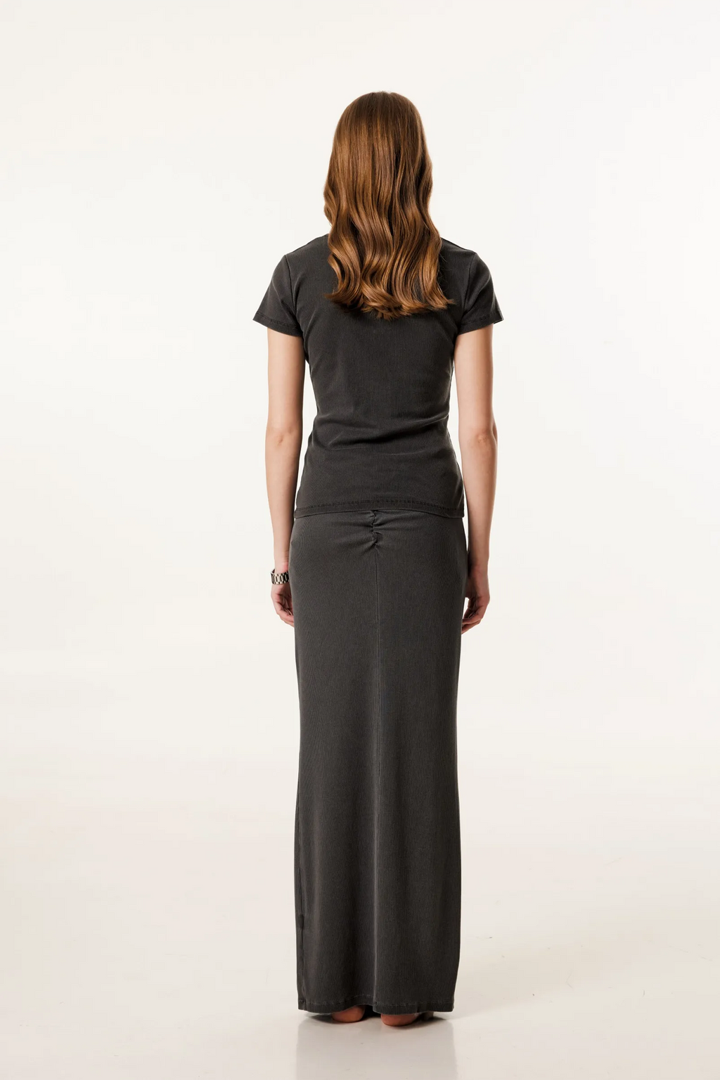 Woman wearing a black t-shirt and long black skirt on a white background