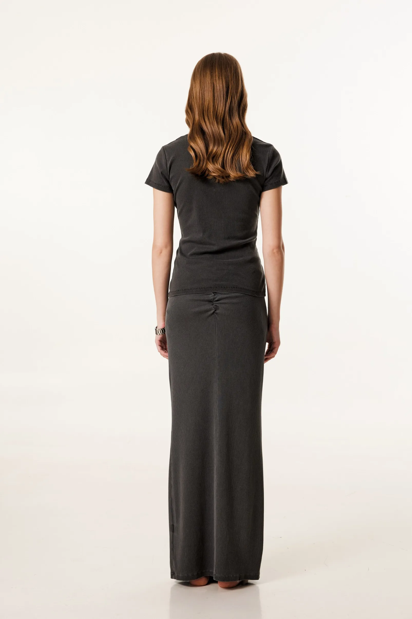 Woman wearing a black t-shirt and long black skirt on a white background